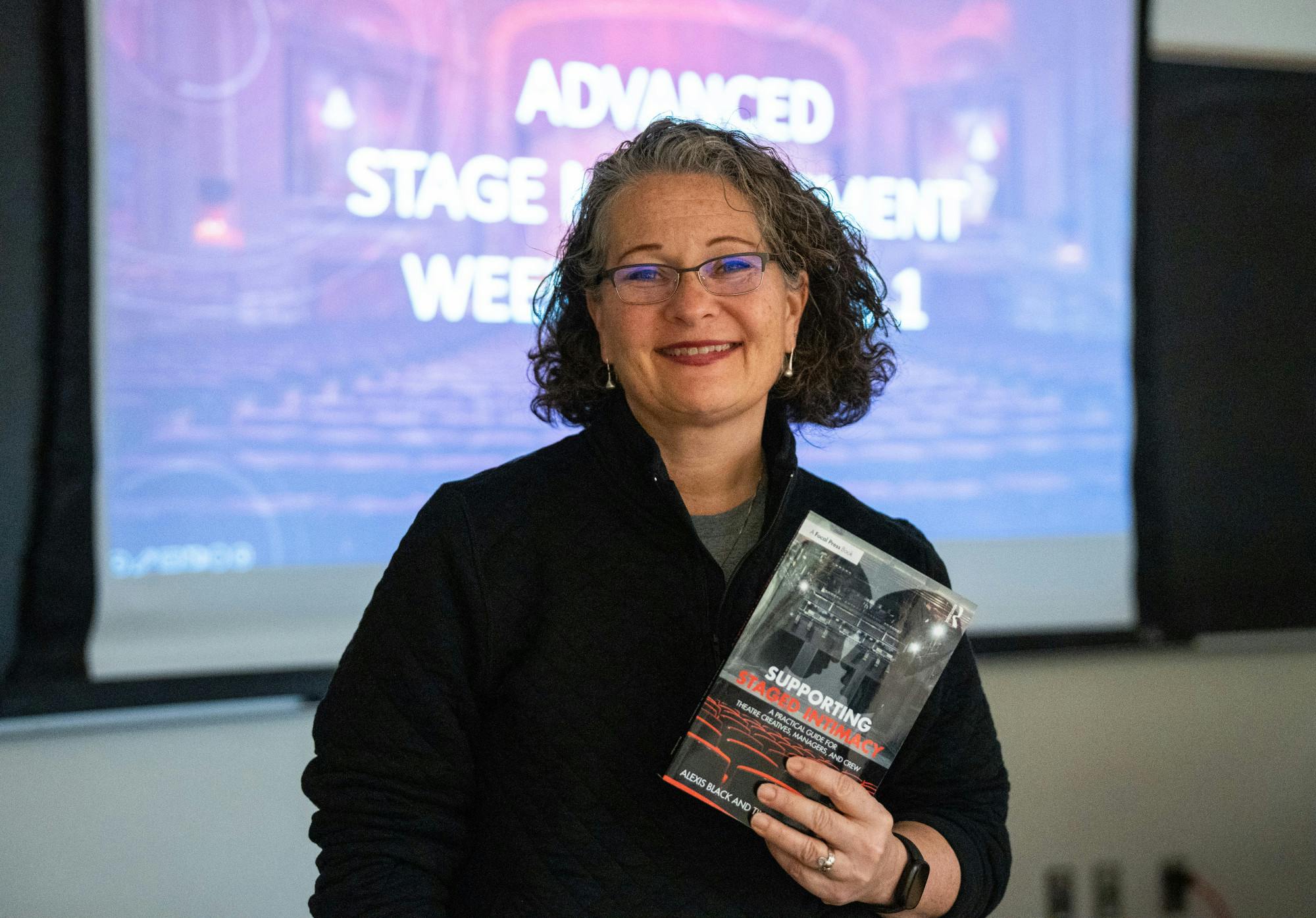 <p>MSU head of Bachelor of Fine Arts in Stage Management and a professor in the theater department, Tina Newhauser poses with her book "Supporting Staged Intimacy" before her Advanced Stage Management class in Snyder-Phillips Hall on April 4, 2023. She co-authored the book alongside her colleague Alexis Black.</p>