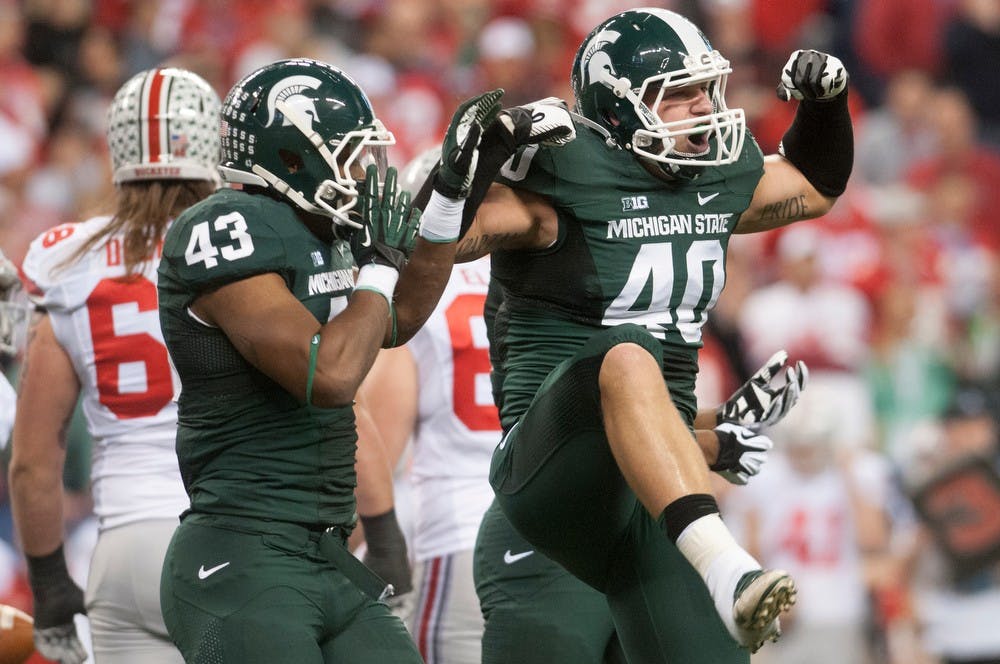 <p>Then-sophomore linebacker Ed Davis, 43, and senior linebacker Max Bullough celebrate tackling Ohio State quarterback Braxton Miller on Dec. 7, 2013, at Lucas Oil Stadium in Indianapolis during the Big Ten Championships. The Spartans defeated the Buckeyes, 34-24. Julia Nagy/The State News</p>