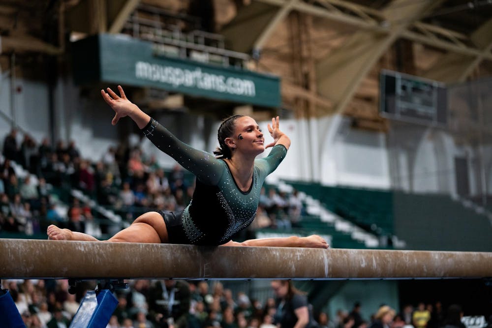 <p>Senior Baleigh Garcia does the splits on a beam during a meet against the University of Maryland at Jenison Field House on Feb. 18, 2024.</p>