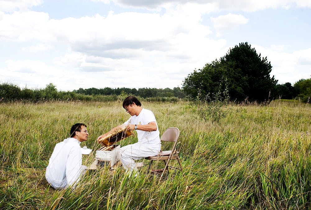 	<p>Associate professor of entomology Zachary Huang holds out a cell of bees for first year postdoctoral entomology student Alex Xie to look at as they do observations for their research on Aug. 30 2011, at the <span class="caps">MSU</span> Inland Lakes Water Research lot. State News File Photo</p>