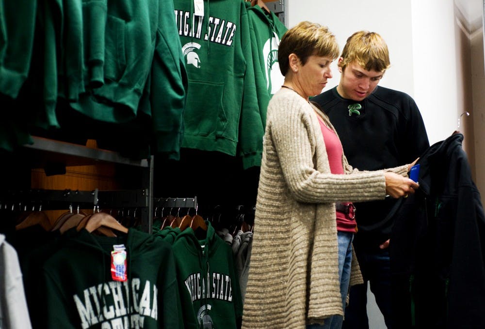 Finance freshman Eric Gaviglio and his mother Jean check out a MSU jacket at Campus Street Sportswear on Friday afternoon. The Gaviglios flew in from New Jersey that morning to attend the Michigan vs. Michigan State football game, as Gaviglio's father Bob is an MSU alumnus. Lauren Wood/The State News