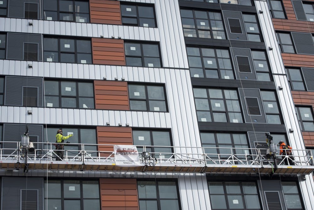 <p>Construction workers work at the Center City Project along Grand River Avenue on Feb. 14, 2019. Nic Antaya/The State News</p>