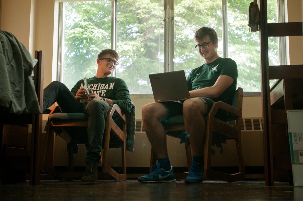 <p>Biophysics junior Charlie Cox, left, and physics junior Gergo Pinter hang out on Aug. 28, 2015, in their West McDonnel dorm room. The two are international students from England. Catherine Ferland/The State News</p>