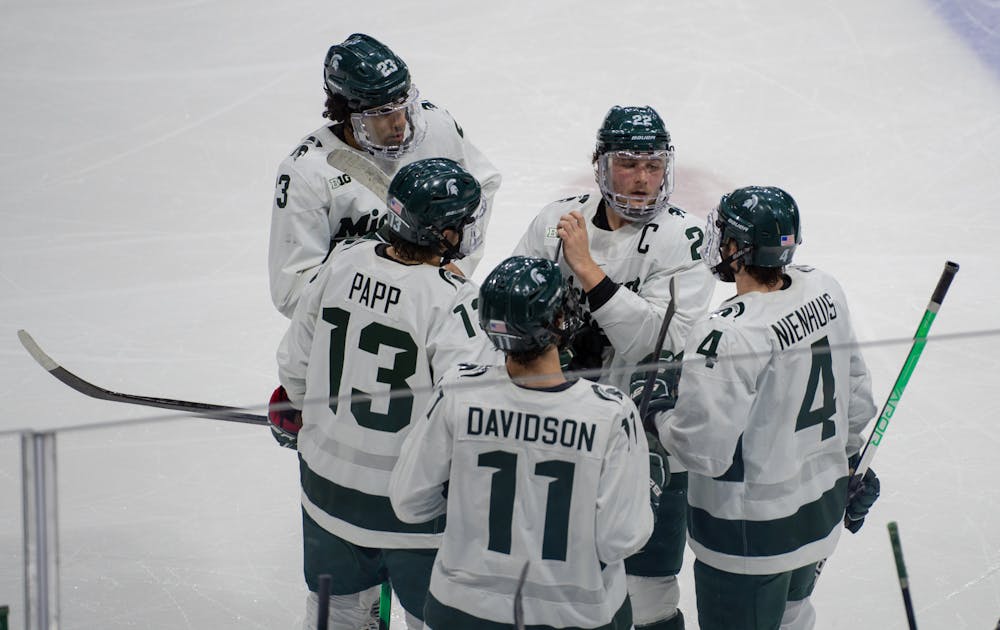 <p>Team members surround senior right defenseman Dennis Cesana (22) in between plays in the first period. The Spartans fell to the Buckeyes, 4-1, at Munn Ice Arena on Jan. 21, 2022. </p>