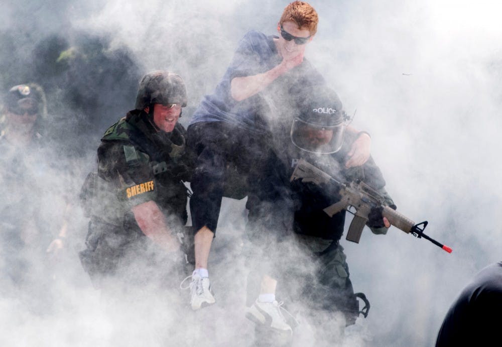 Two law enforcement officers carry off Holt resident Tim Whitford, an LCC psychology sophomore, during an active shooter scenario outside of the MSU Pavilion on Wednesday afternoon. The scenario involved an explosion going off and law enforcement officers racing the clock to keep the injured alive until an EMS could arrive. Natalie Kolb/The State News