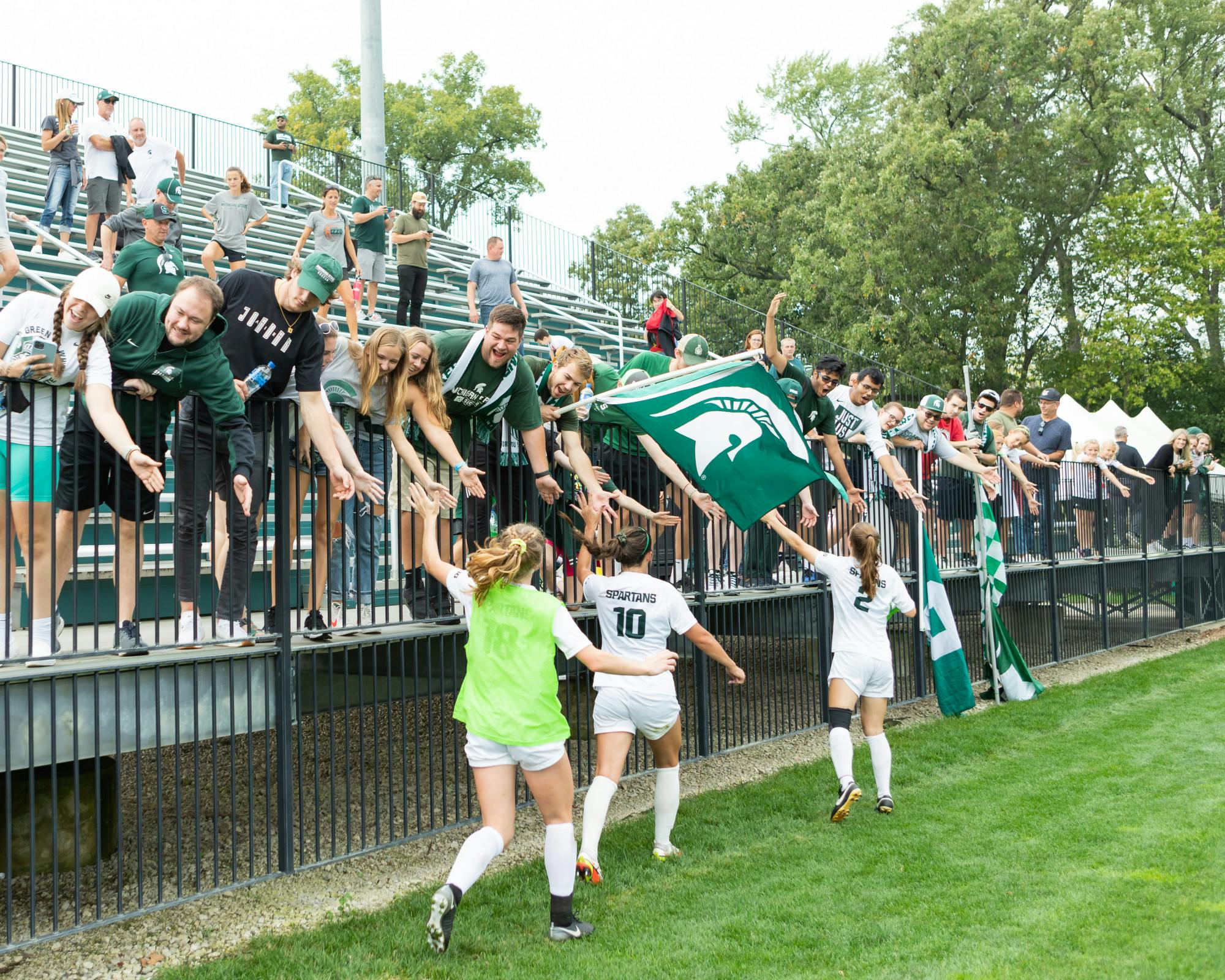 <p>The Michigan State University women’s soccer team runs to greet fans after their victory. Shot on Oct. 10, 2021.</p>