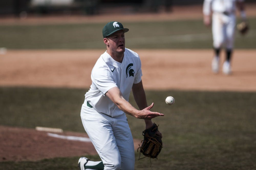 Redshirt senior pitcher Ethan Landon (7) underhand tosses the ball to first base during the game against the University of Michigan on March 24, 2018 at McLane Baseball Stadium. The Spartans fell to the Wolverines, 3-1. (C.J. Weiss | The State News)