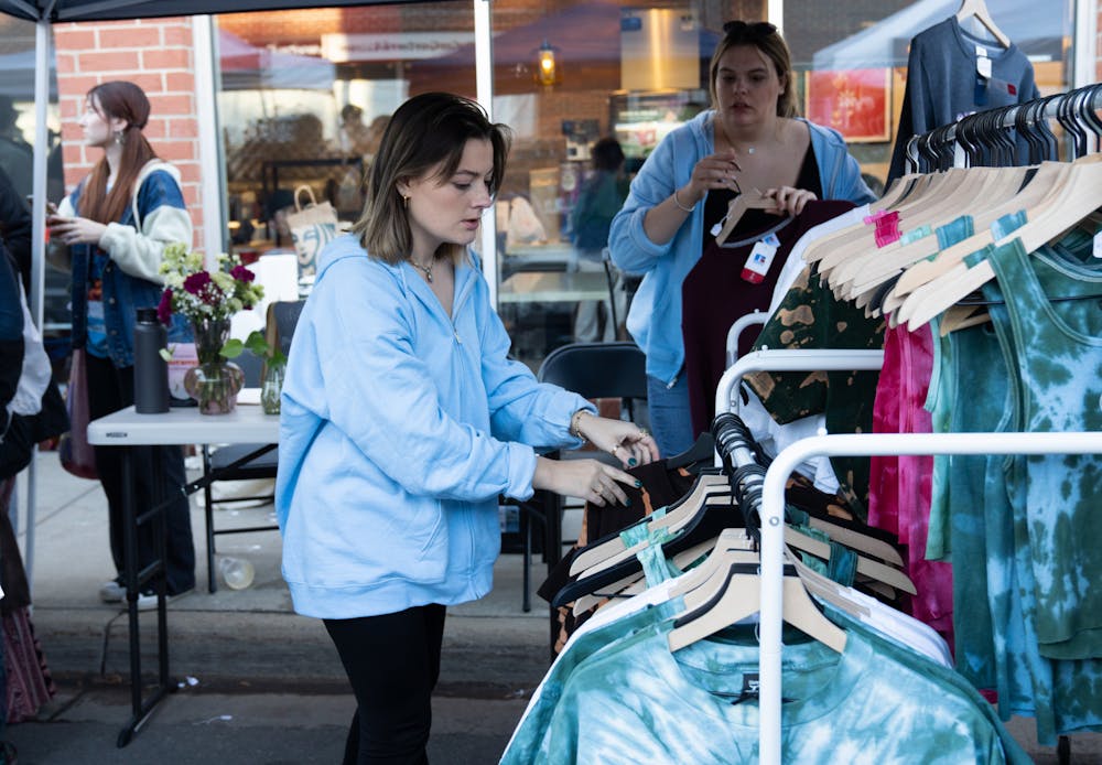 <p>Owner of Blu Threads and Co., Megan Timmerman sorts through her clothing selection at the first annual Vintage Fest in East Lansing on Oct. 1, 2022. </p>