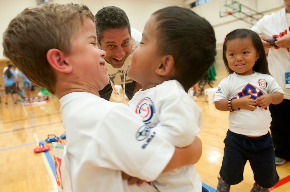 	<p>Brighton, Mich., resident Joey Tarnacki, 6, picks up Colorado Springs, Colo., resident Tao Kreb, 3, to congratulate him on his silver medal Aug. 7, 2013, at the kurling event in IM Sports-West during the 2013 World Dwarf Games. Kreb&#8217;s sister, Feifei, 6, and coach Bill Tarnacki smile in the background. Julia Nagy/The State News</p>