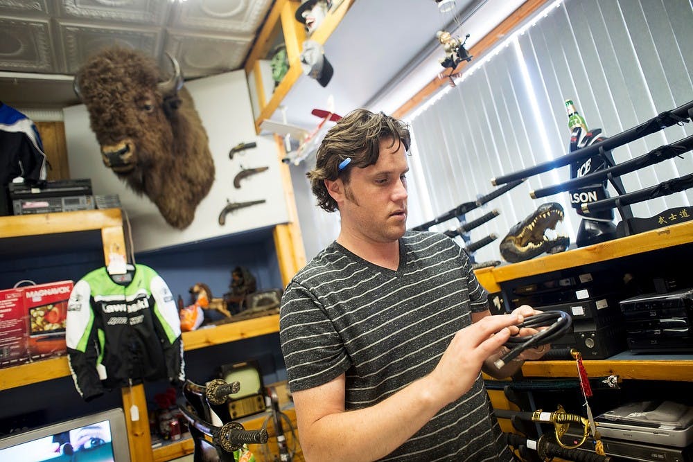 	<p>Stacey Potter, manager of  Dicker &amp; Deal Second Hand Store, picks up a TV cable for a customer on July 19, 2013, at the store&#8217;s location at 1701 S. Cedar Street in Lansing. It is the second-oldest store in the Lansing area. Justin Wan/The State News</p>