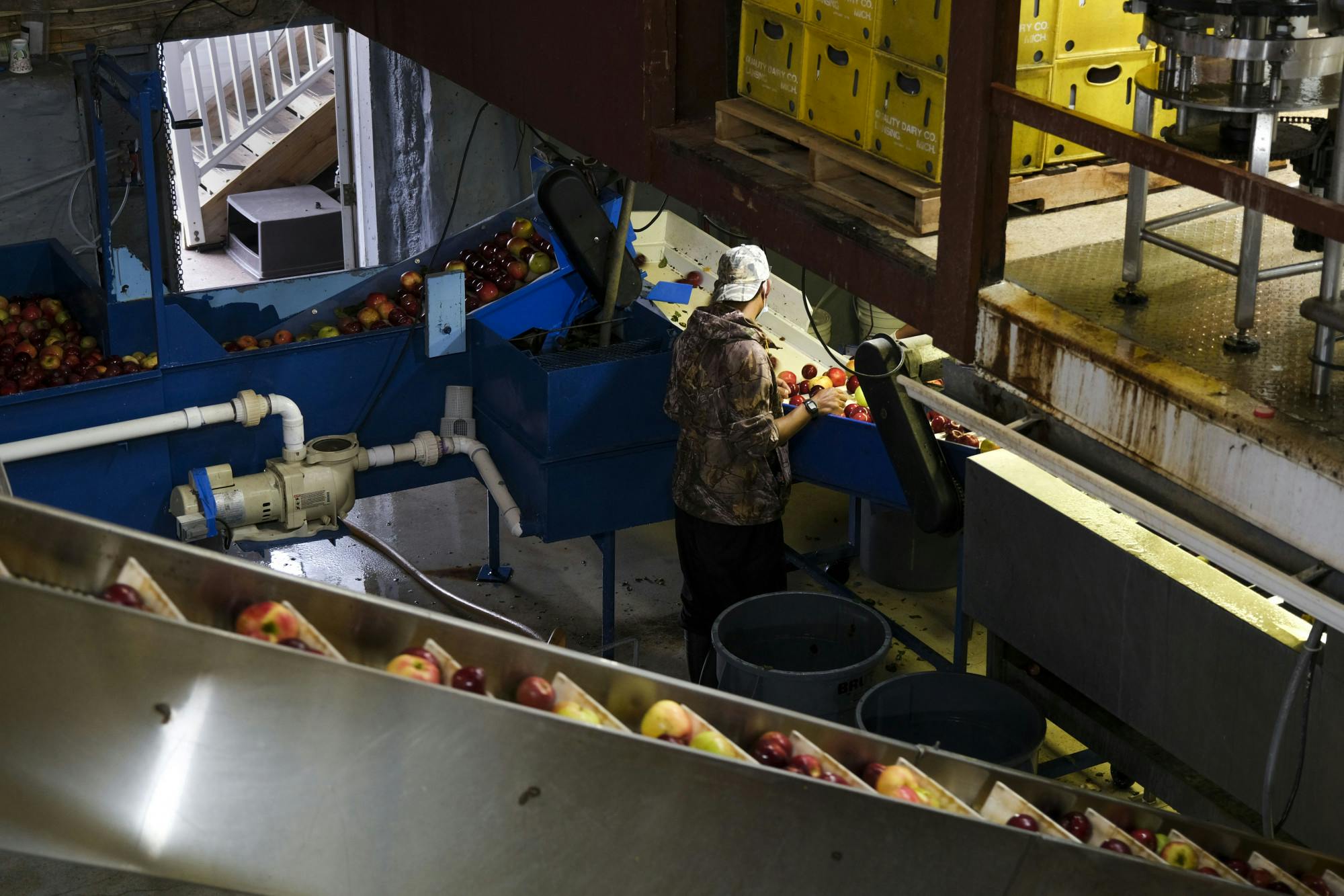 An employee at Uncle John's Cider Mill is surrounded by machinery where cider is made.