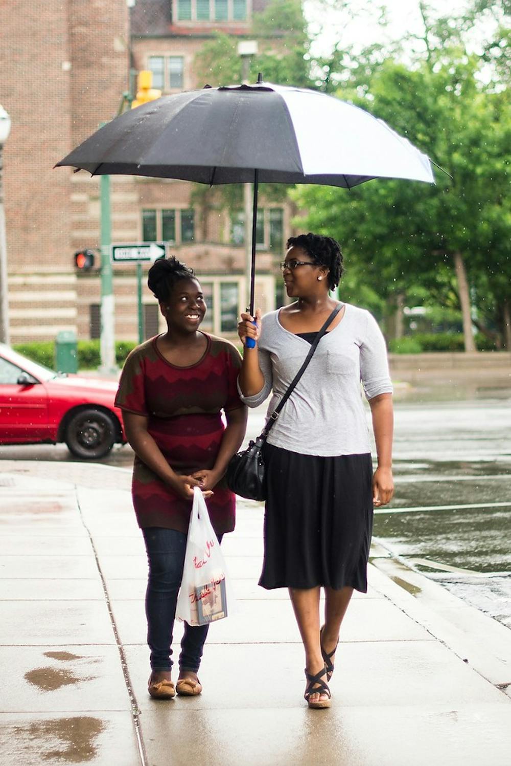 <p>Lansing residents Danielle Brown, left, and Jumoke Shoneye, right, try to stay dry June 4, 2014, on East Grand River in front of Cosi. It rained most of the day in the East Lansing area, dropping the temperature into the 60s. Hayden Fennoy/The State News</p>