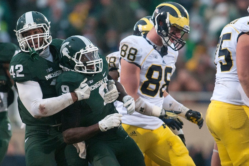 	<p>Senior defensive end Denzel Drone pulls senior safety Isaiah Lewis from from a huddle of Wolverines on Nov. 2, 2013, at Spartan Stadium. The Spartans won, 29-6. Julia Nagy/The State News </p>