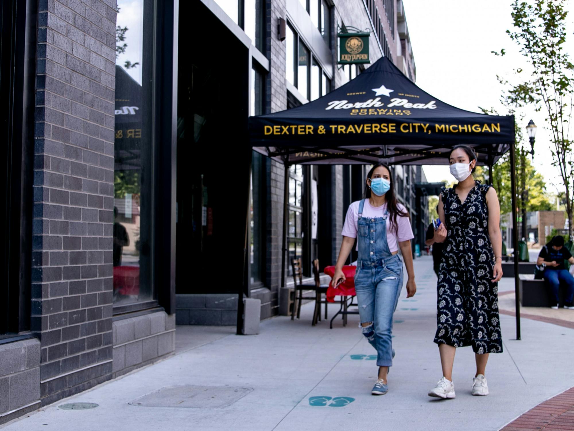 Two people walk in front of Jolly Pumpkin in East Lansing wearing their masks August 24, 2020.