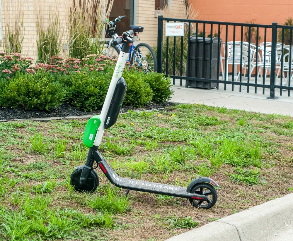 A Lime scooter is pictured parked next to the sidewalk on Grand River Ave.