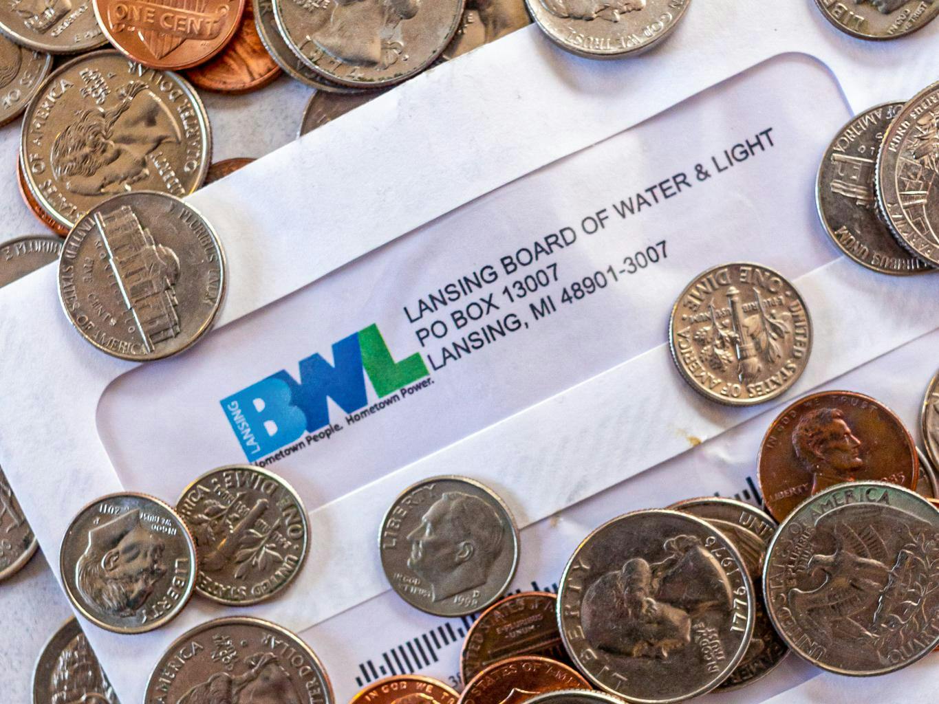 <p>Coins and a Lansing Board of Water and Light bill photographed on April 7, 2020.</p>