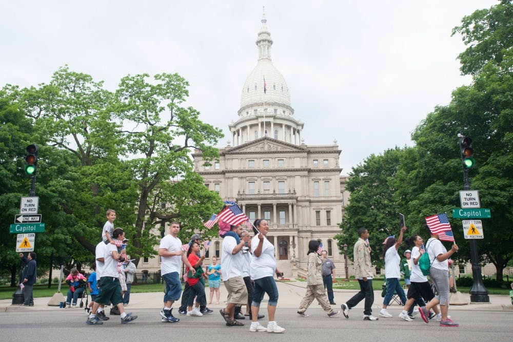 Family members and friends honor Ricky Rosa, who passed away during his service in Iraq, walk past state Capitol on Saturday, May 26, 2012 morning in downtonwn Lansing during Memorial Day Parade. Justin Wan/The State News