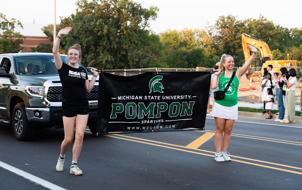 Two members of MSU's Pompon team lead a group through campus at the MSU Homecoming Parade on Friday, Sept. 22. The team danced and waved to onlookers on the side of the road.