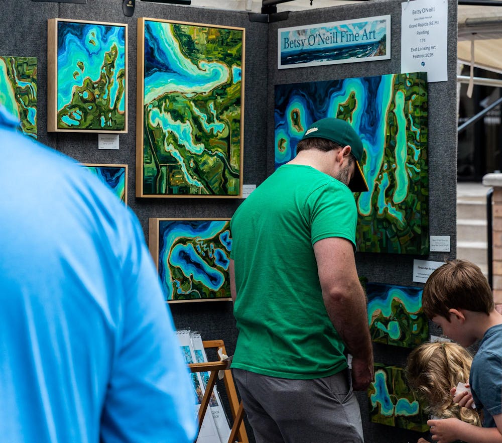 <p>A father and his children look at Betsy O'Neill's fine art booth at the 63rd annual East Lansing Art Festival in East Lansing, Mich., on May 16, 2026.</p>