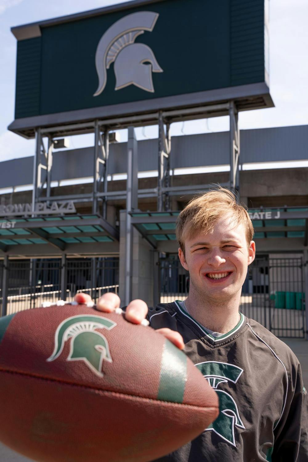 <p>Kaspar Haehnle, a reporter with The State News, poses with a football outside Spartan Stadium, March 11, 2024. Haehnle took part in the Varsity Football tryouts for the Spartans to get a closer look at what it takes to make the team.</p>
