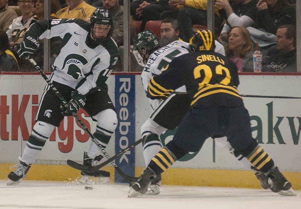<p>Freshman defenseman Carson Gatt and Sophomore forward Mackenzie MacEachern fight for the puck during the game against Michigan on Jan. 30, 2015, at Joe Louis Arena in Detroit, Michigan. The Spartans beat the Wolverines 2-1. Alice Kole/The State News</p>