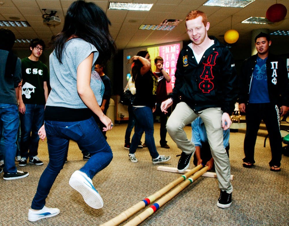 Civil engineering junior Jane Lee and anthropology junior Josh Jennings perform a Filipino dance called Tinikling, which involves hitting two bamboo sticks on the ground in coordination with dancers. The activity was one of several at Night Market that introduced students to different Asian American cultures on Monday night at Wonders Hall Kiva. Josh Radtke/The State News