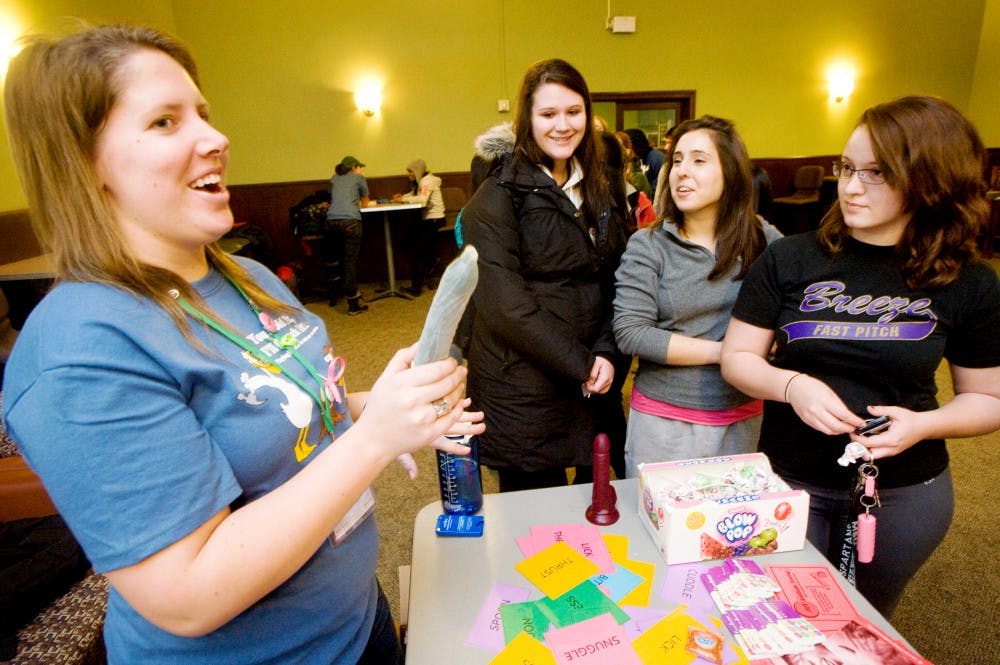 From left, dietetics senior and sexual health advocate Cara Gabris explains steps to wear a condom to pre-nursing sophomore Cheyenne Woods, communications sophomore Brittany Durham, and advertising junior Bethany Morrill Monday night at Shaw Hall during a Duck Days event hosted by Olin Health Center. The on-campus health clinic promoted various education opportunities at the event and had free MSU Social Norms T-shirts for participating students.  Justin Wan/The State News
