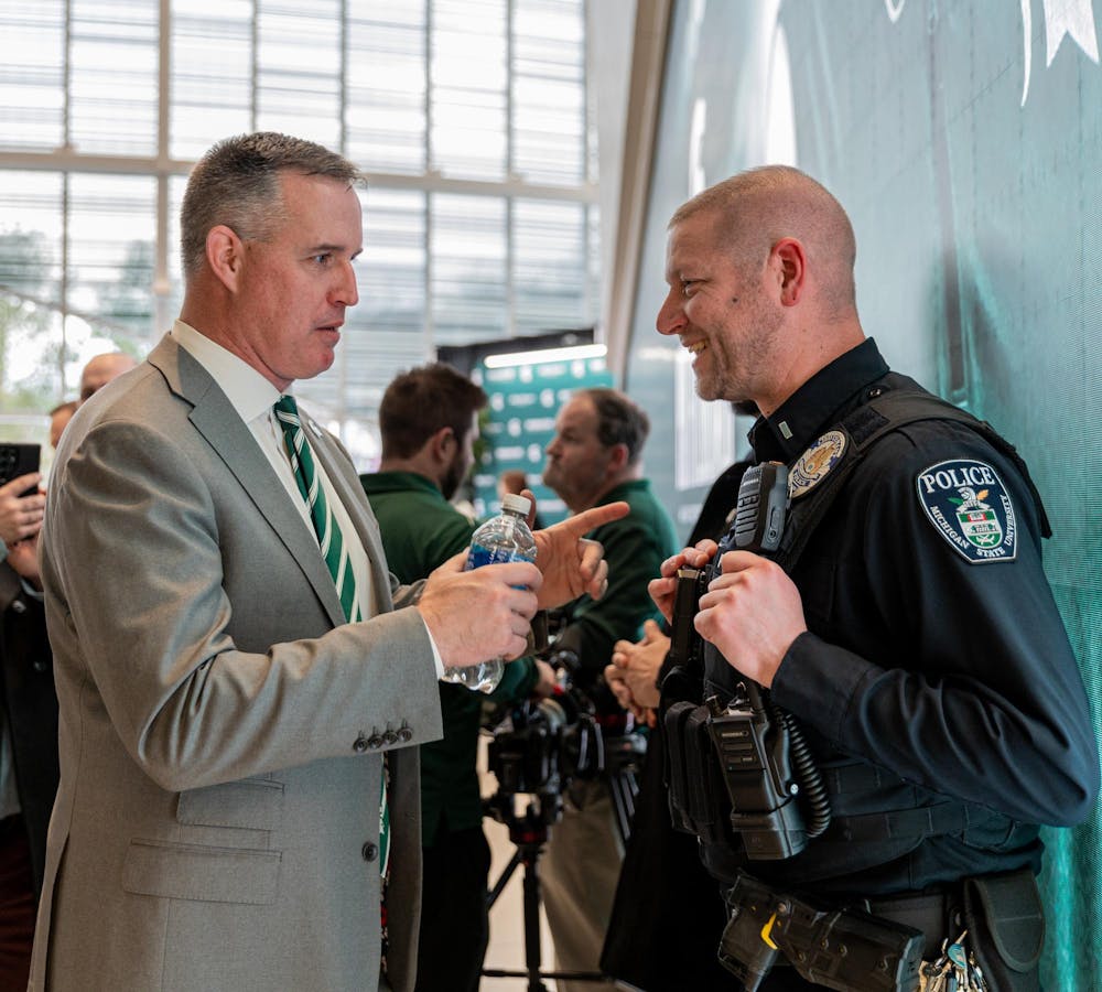 MSU's new football HC Pat Fitzgerald jokes around with an MSU Police Officer in the Tom Izzo football building in East Lansing, MI on Dec. 2, 2025.