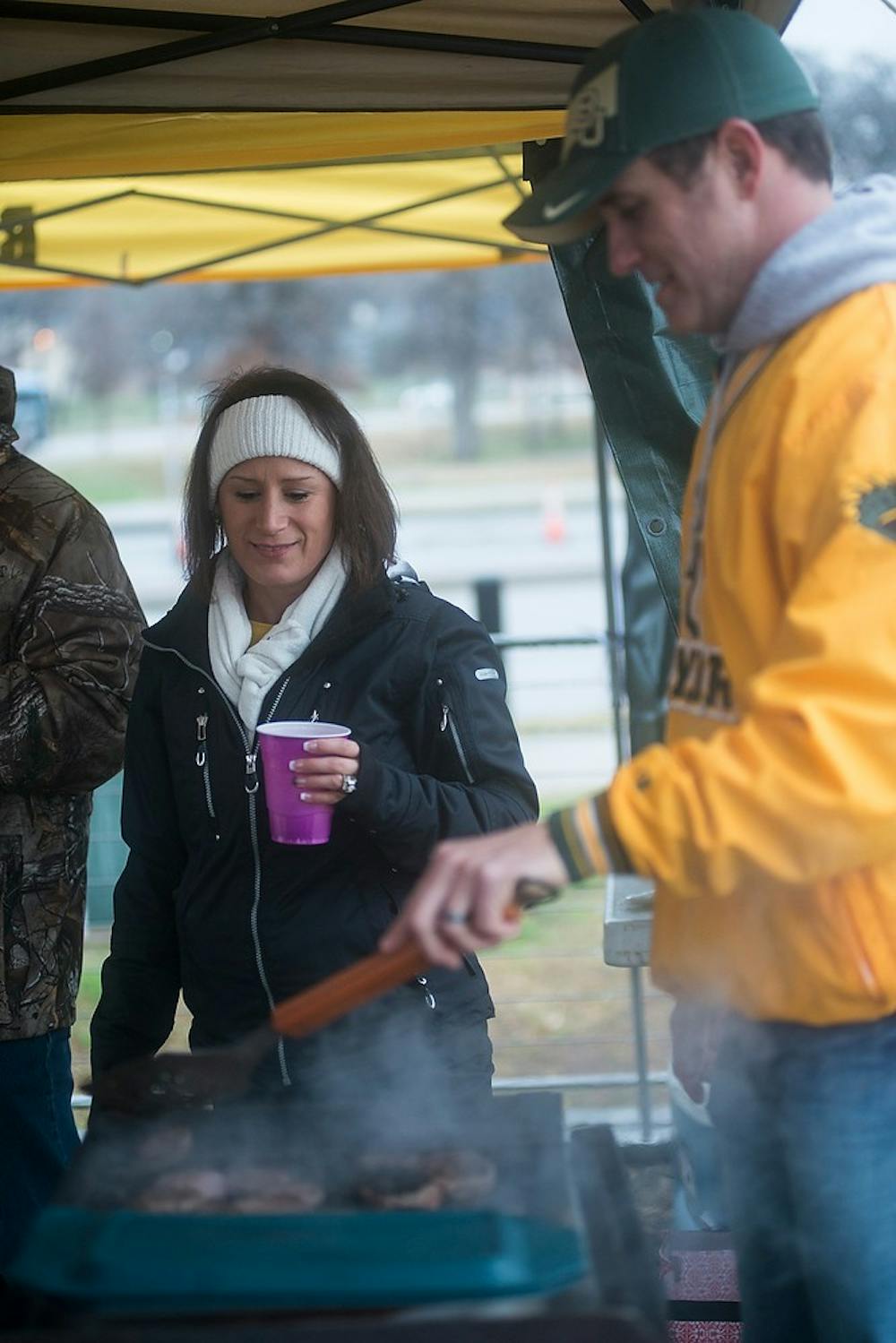 <p>Rockwall, Texas residents and Baylor fans Dee Dee and Rick Flynt cook sausage under their tent Jan. 1, 2015, while tailgating before The Cotton Bowl Classic football game against Baylor at AT&T Stadium in Arlington, Texas. It was 34 degrees in Dallas with showers. Erin Hampton/The State News</p>