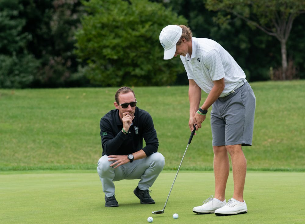 <p>Head Coach Casey Lubahn directs fifth-year senior James Piot at Lasch Family Golf Center on Sept. 21, 2021.</p>
