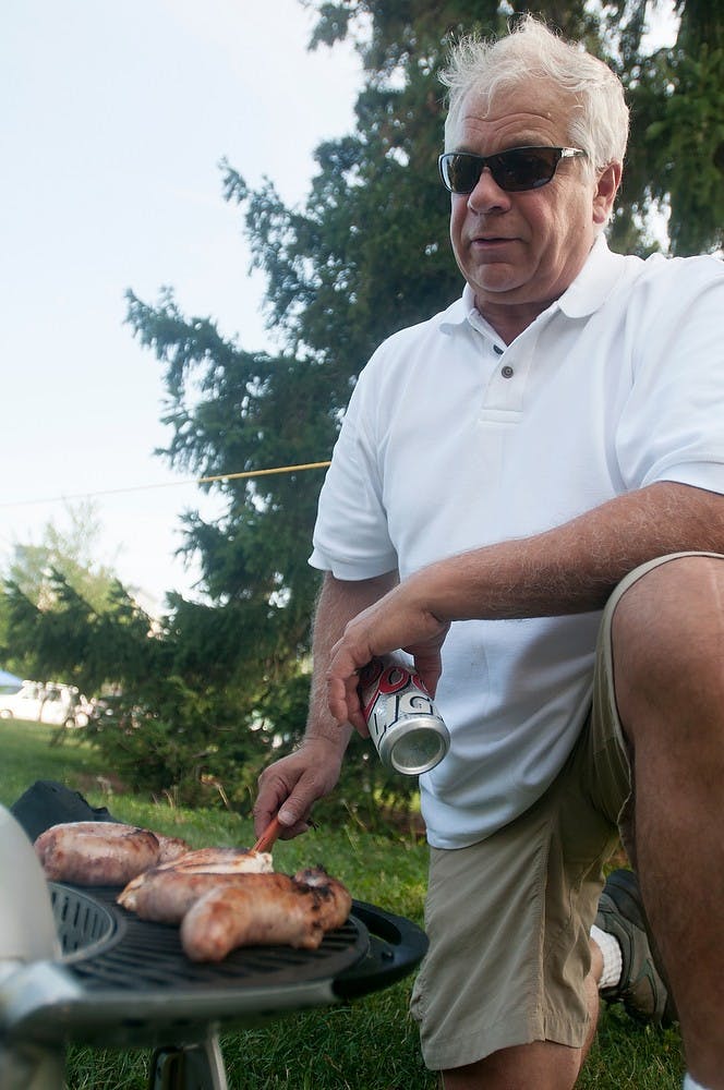 	<p>Pleasant Ridge, Mich. resident Joe Stroker cooks on a portable grill on Aug. 30, 2013, outside of Spartan Stadium. Stroker cooked chicken and bratwurst. Katie Stiefel/The State News</p>