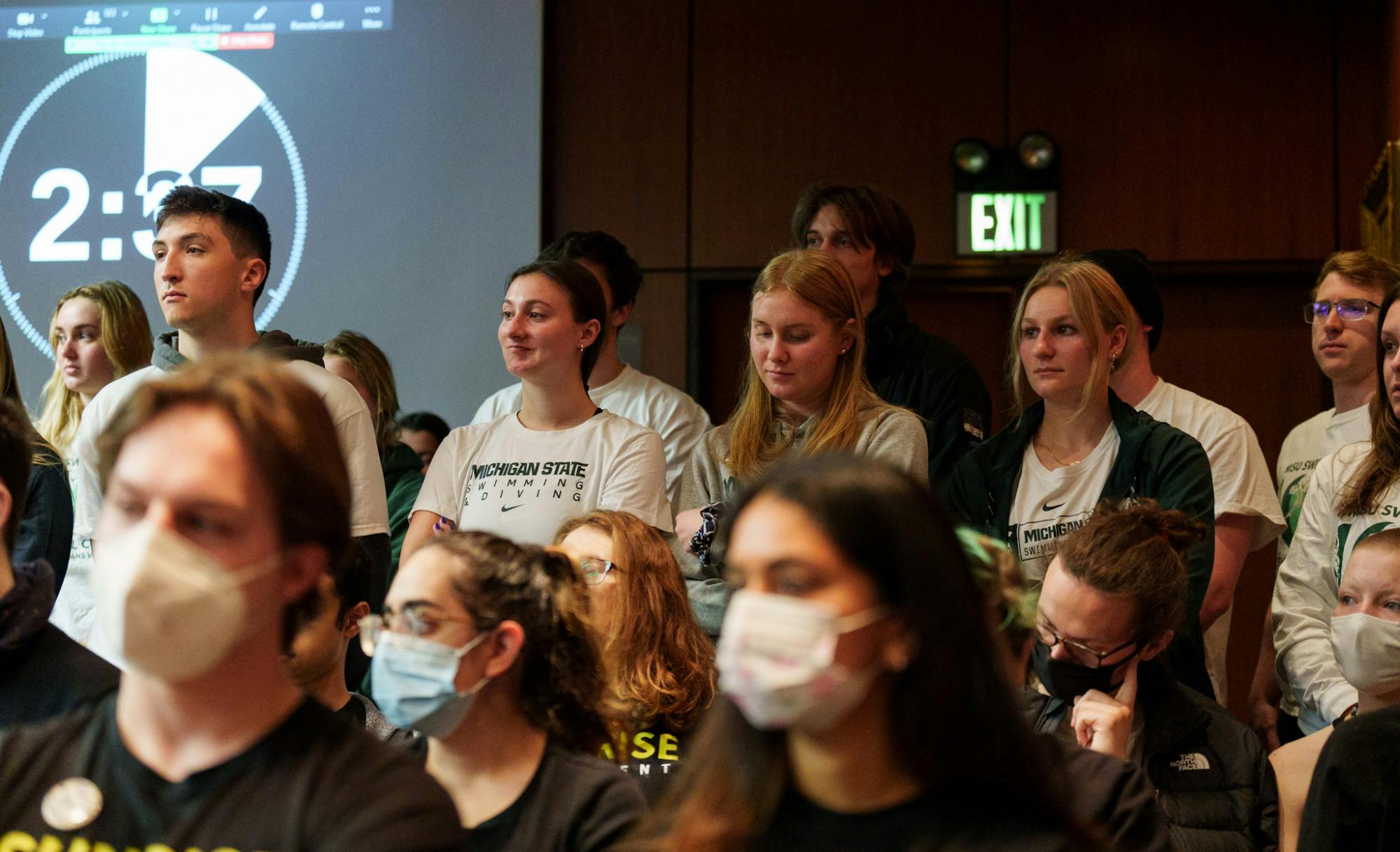 <p>The Michigan State University Board of Trustees met in the Hannah Administration Building on April 22, 2022. Supporters of the reinstatement of the varsity swim and dive team stand during their peer&#x27;s public comment. </p>