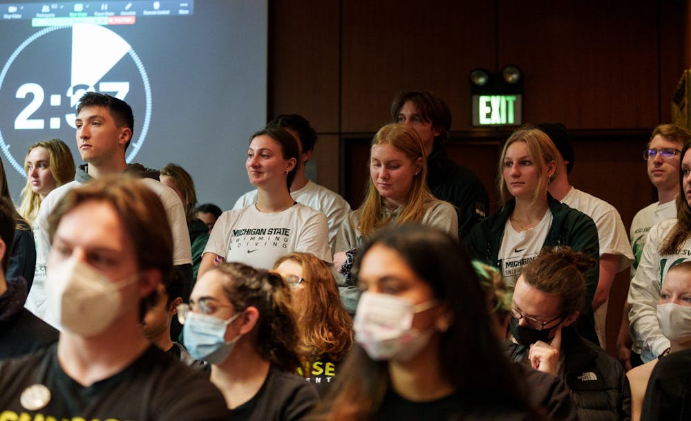 <p>The Michigan State University Board of Trustees met in the Hannah Administration Building on April 22, 2022. Supporters of the reinstatement of the varsity swim and dive team stand during their peer&#x27;s public comment. </p>