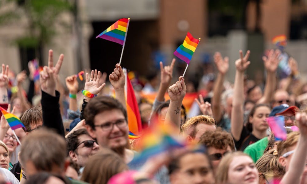 <p>Rally attendees hold up pride flags and peace signs during the 2019 Michigan Pride Rally at the Michigan Capitol on June 15, 2019.</p>