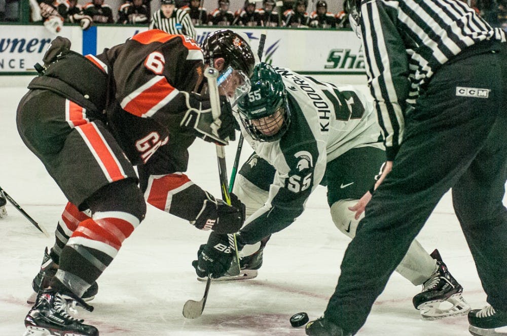 Senior forward Mitch McLain (6) and sophomore forward Patrick Khodorenko(55) fight for the puck during a face-off on Oct. 14, 2017 at Munn Ice Arena. The Spartans defeated the Falcons 3-2 with seconds left in the game. 