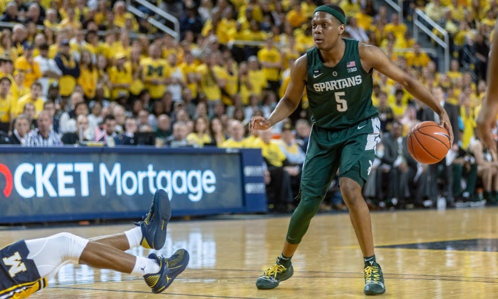 <p>Junior guard Cassius Winston (5) crosses over a Michigan player. The Spartans beat the Wolverines, 77-70, on Feb. 24, 2019 at the Crisler Center.</p>