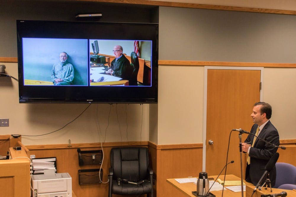 Attorney John Dakmak speaks to judge Richard D. Ball as former MSU dean William Strampel watches over video during his arraignment at the 54-B District Court on March 27. Strampel faces four charges, misconduct in office, a five-year felony, two counts of willful neglect of duty and one count of fourth-degree criminal sexual conduct.