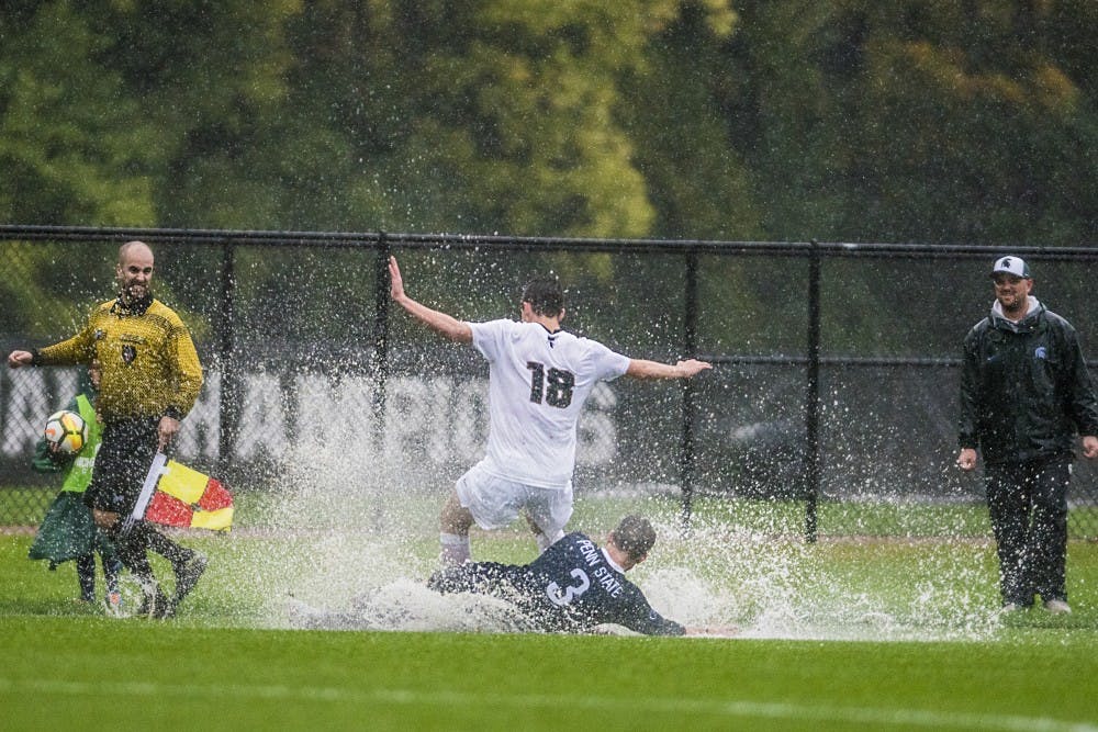 Freshman midfielder Michael Miller (18) falls over Penn State defense Brandon Hackenberg (3) during the game against Penn State on Oct. 14, 2017 at DeMartin Stadium. The Spartans defeated the Nittany Lions in the pouring rain, 1-0.