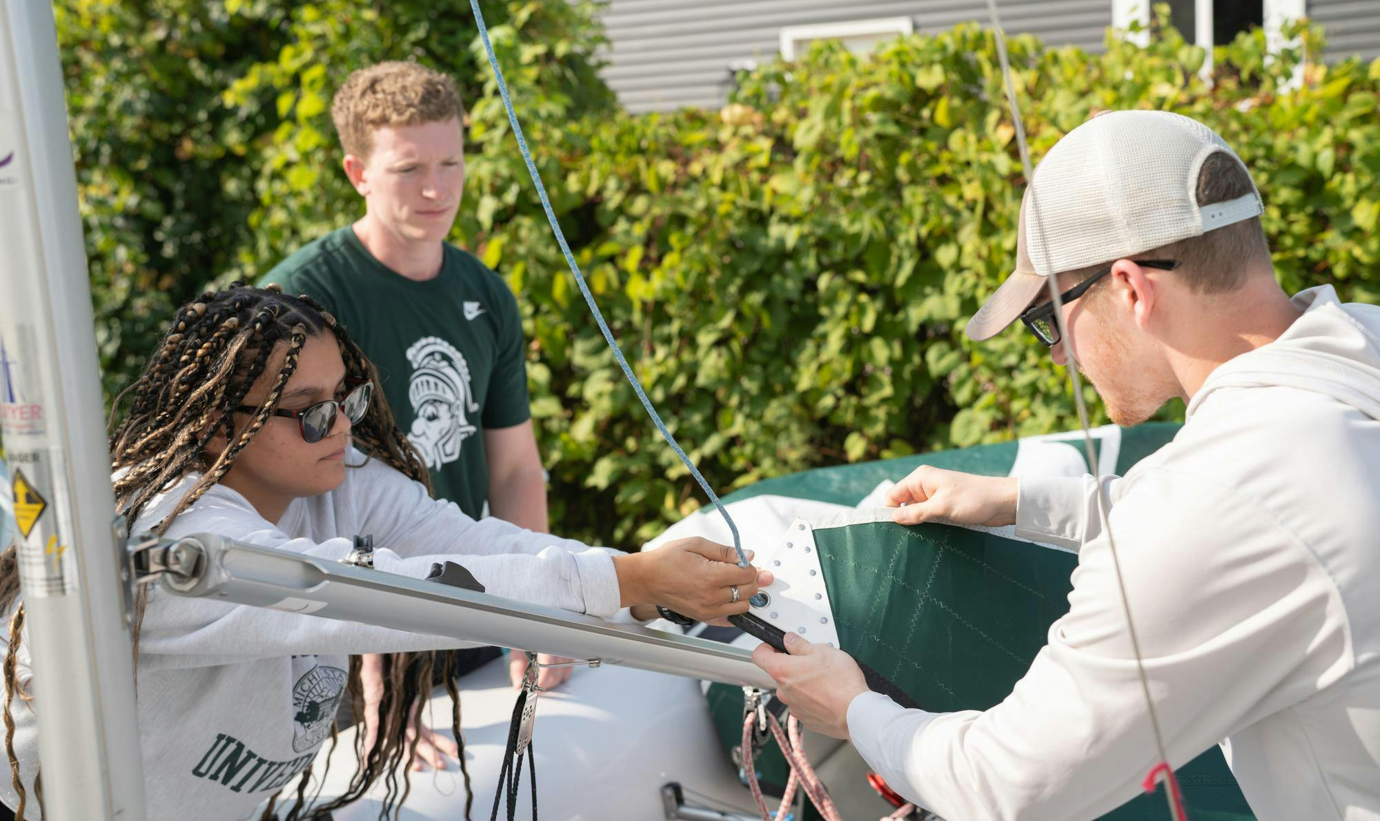 <p>Michigan State University Sailing Center staff member and political science senior AJ Williams, left, helps civil engineering junior Daniel Wenk, right, rig his boat's sail ahead of the class's first day on the water on Sep. 10, 2024.</p>