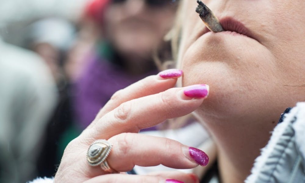 <p>A woman smokes a joint on April 2, 2016 at Hash Bash in The Diag in Ann Arbor, Mich. Hash Bash is an annual event that hosts vendors, music and guest speakers.</p>