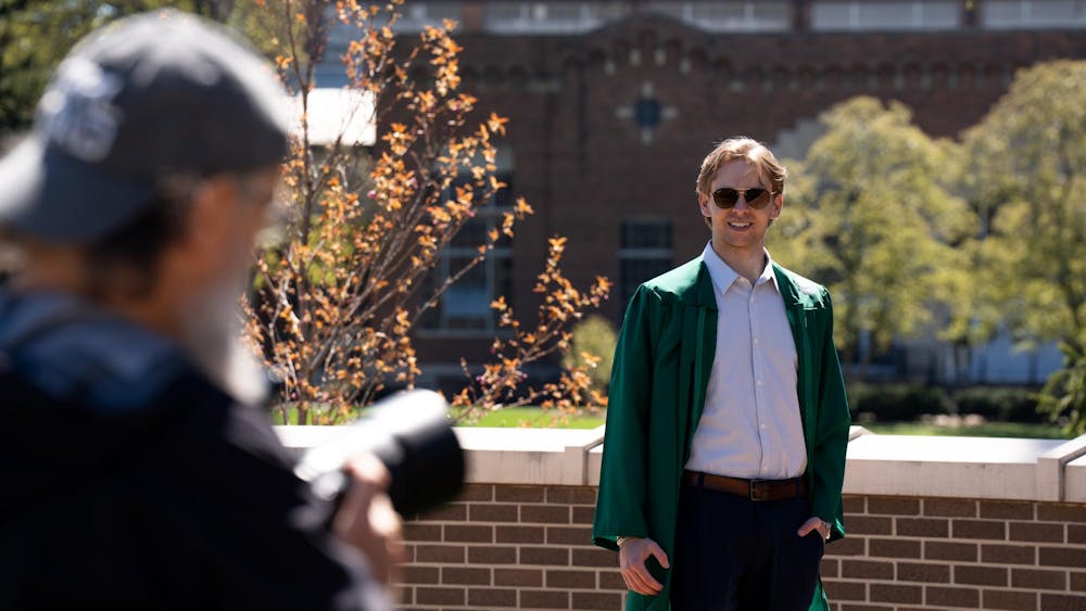 Alex Seibel, a finance senior, poses for his portrait at the Sparty Statue on campus on April 19, 2024. Seniors often have to wait in line for the best spots on campus to get their portraits taken. 