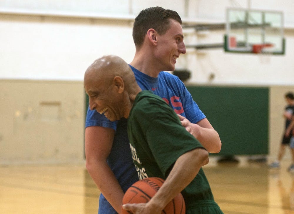 <p>East Lansing resident and 1965 MSU alumnus James E. Cummings Jr. embraces mechanical engineering freshman Kevin Schuett after a game of HORSE April 22, 2015, at IM West in the gym where he had a heart attack three and a half years ago. Cummings comes to the gym nearly every day to practice his shot and play HORSE with "young spartans." Kennedy Thatch/The State News</p>