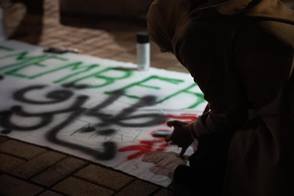 "Say his name," writes human biology junior Aesha Zakaria onto a banner at an anniversary memorial for Michigan State Humphrey fellow and Israeli bombing victim Tariq Thabet on Oct. 30, 2024. Zakaria was in contact with Thabet shortly before his death last year.