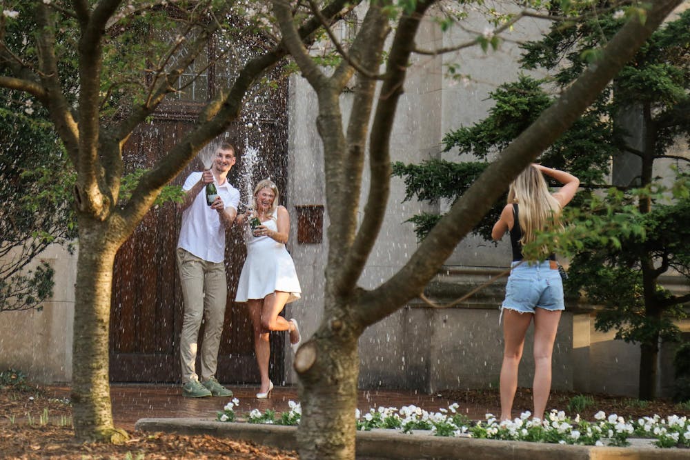 <p>Carson Cooper, a senior on the Michigan State men’s basketball team, and Mara Schrauben pop champagne after getting engaged at Beaumont Tower in East Lansing, Mich., Thursday, April 24, 2026.</p>