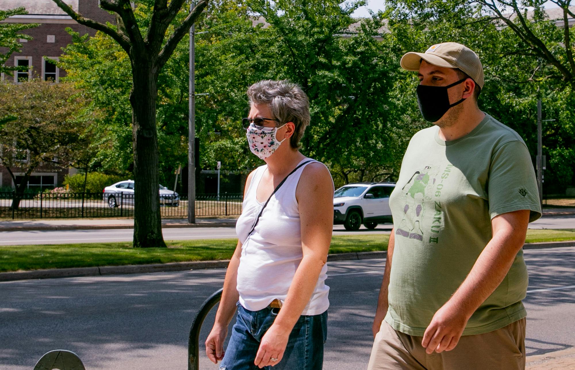 Two people walk in downtown East Lansing wearing their masks August 24, 2020.