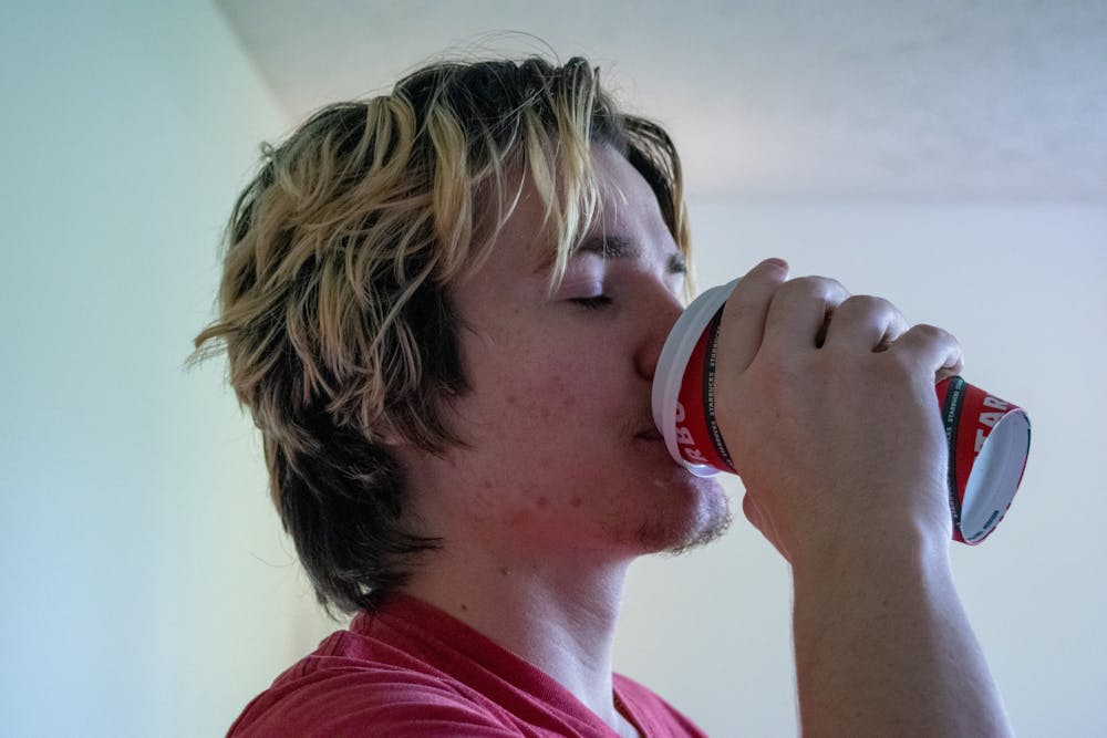 <p>Advertising junior Tommy Wehr takes a sip of hot chocolate out of a Starbucks 2021 holiday cup.</p>