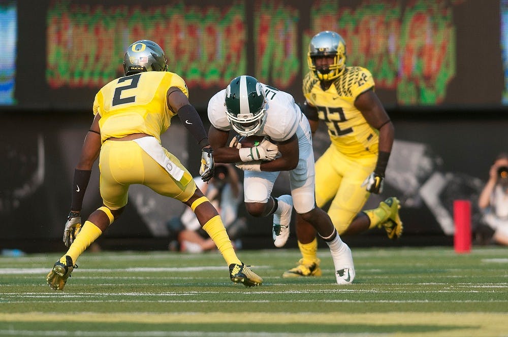 <p>Senior wide receiver Tony Lippett braces for Oregon defensive back Tyree Robinson's tackle on Sept. 6, 2014, at Autzen Stadium in Eugene, Ore. The Spartans lost to the Ducks, 46-27. Julia Nagy/The State News</p>