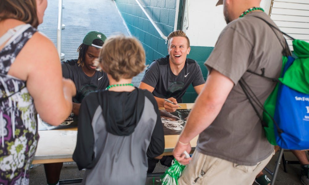 Sophomore quarterback Brian Lewerke (14) laughs with a fan during Meet the Spartans on August 23, 2017 at Spartan Stadium. Meet the Spartans is an event where fans are invited to meet football players along with coach Dantonio.