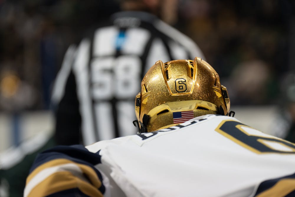 <p>Bright stadium lights shine off of Notre Dame sophomore defenseman Jake Boltmann's gold helmet as he lines up for a faceoff at Compton Family Ice Arena in Notre Dame, IN on Friday, March 3, 2023. Boltman recorded two blocked shots and two penalty minutes during the Friday night victory over the Spartans.</p>