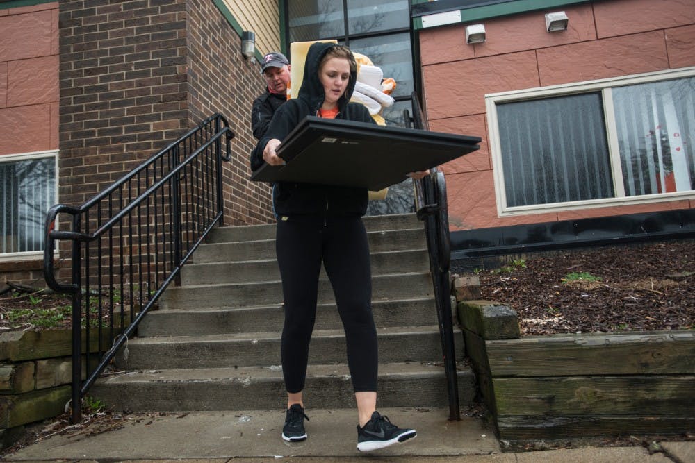 Journalism and media and information senior Anne Abendroth and her father Joel Abendroth carry furnishings from Anne's apartment on March 31, 2016 outside of Abbot Manor at 910 Abbot Road. The building was declared unsafe for human occupancy and it was deemed unlawful for any person to use or occupy the space after 4 p.m. March 30, 2016.
